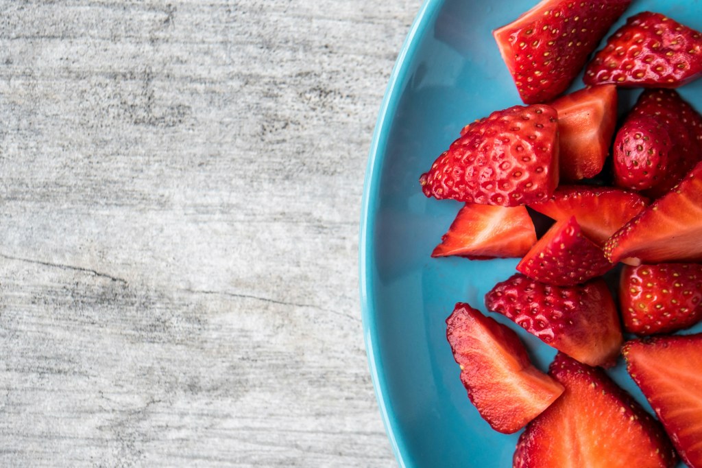 blue bowl of strawberries on a wooden table